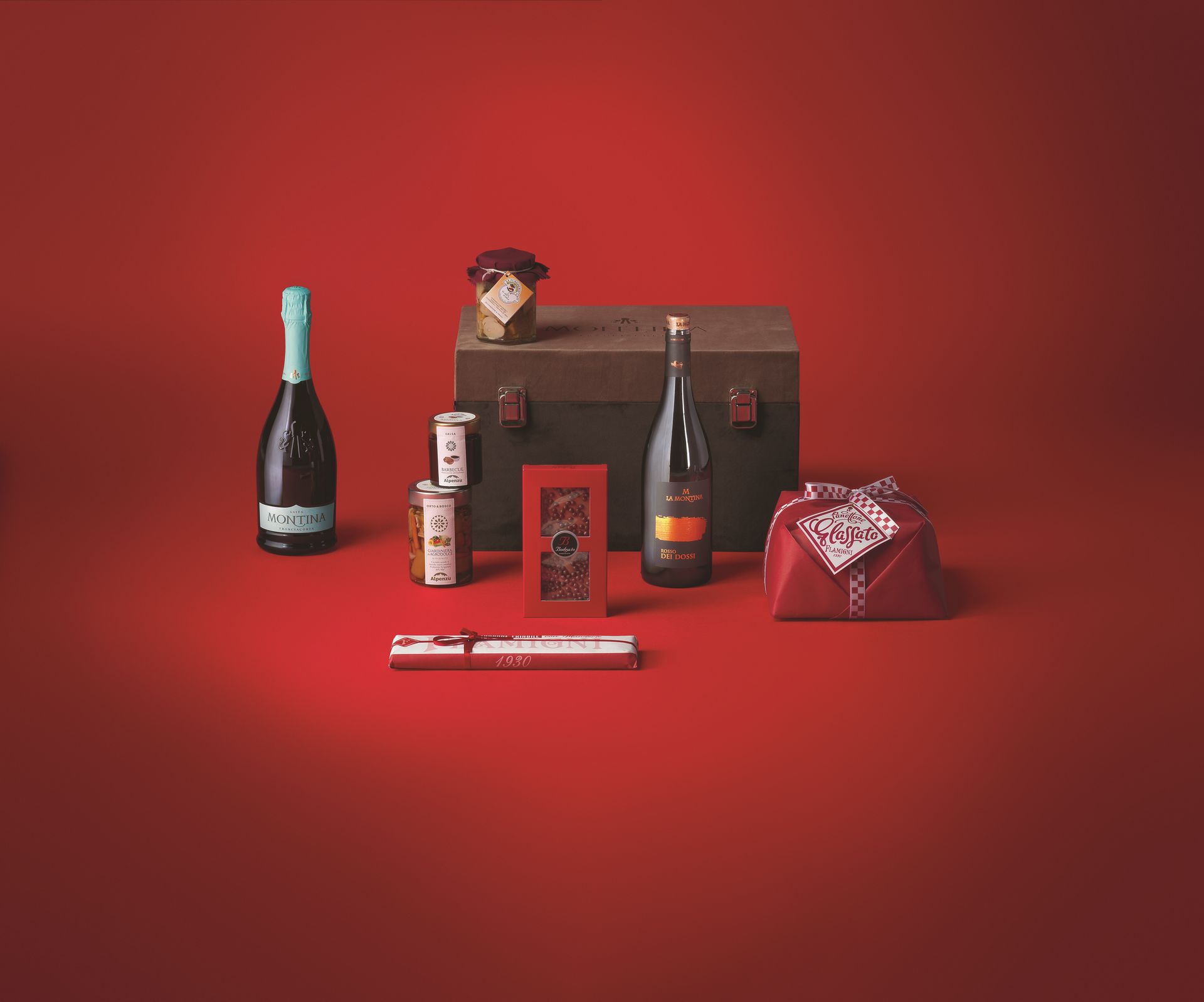 Confezione Natale red night I pacchi natalizi Montina red night bauletto velluto, Franciacorta Satèn e Rosso dei Dossi, panettone, cioccolato, salsa barbecue e funghi porcini.